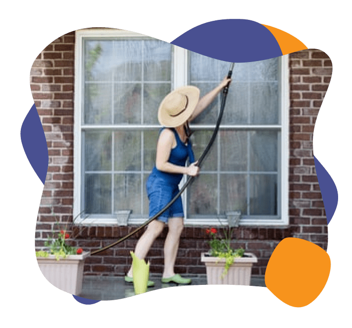 A lady cleaning the exterior of her homes windows. 